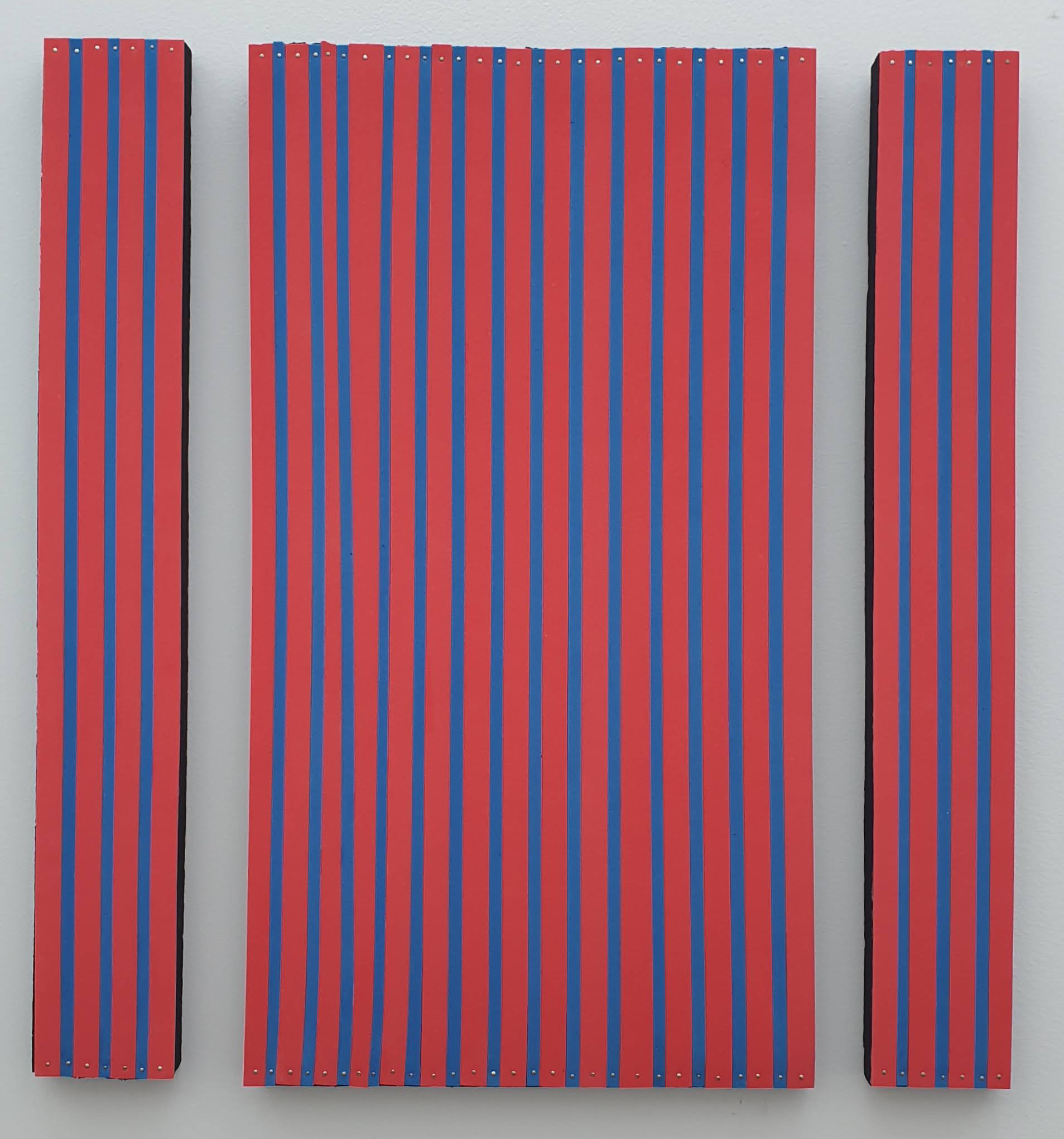 Three panels of raised red strips separated by narrow blue channels, a wide central panel flanked by two narrow ones, each strip pinned with small metal studs top and bottom.