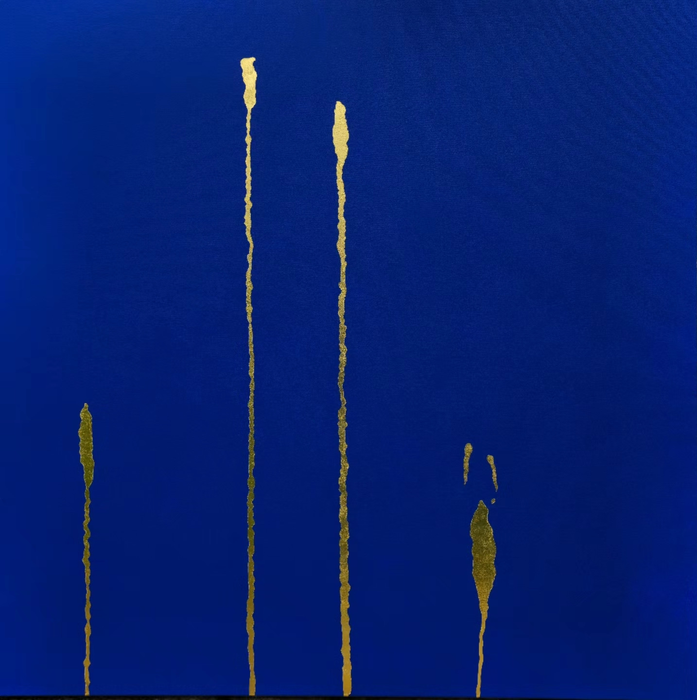 Gold vertical trails on deep blue, two tall and two short, thickening into blunt flames at their tips; a small detached mark hangs in the space beside them.